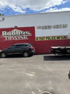 Exterior of Bobby's TCB Towing business building with signage and a tow truck trailer in Detroit, MI