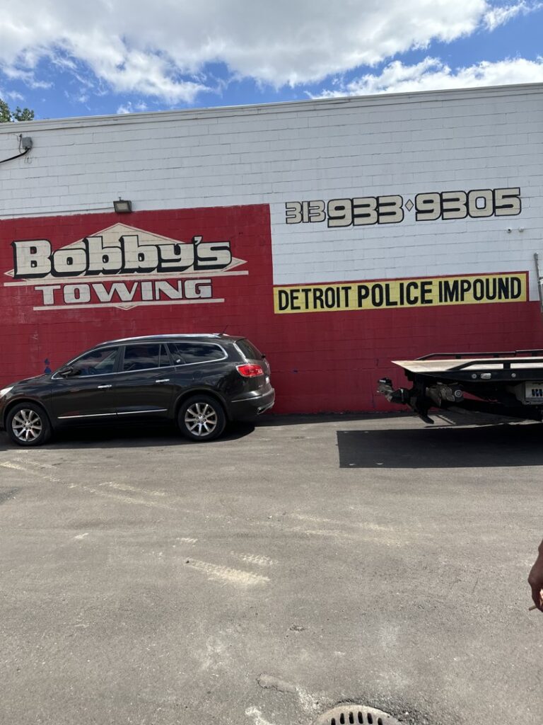 Exterior of Bobby's TCB Towing business building with signage and a tow truck trailer in Detroit, MI