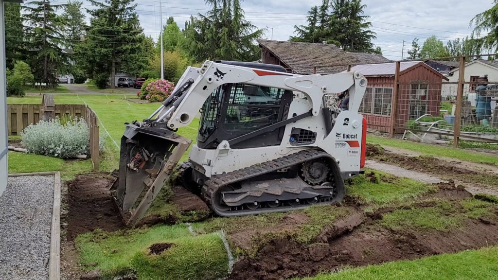 A Bobcat T770 compact track loader clearing a site next to a residential building for ROUGH 2 READY in Auburn, AL