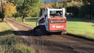 A Bobcat T770 compact track loader grading a dirt path for ROUGH 2 READY in Auburn, AL