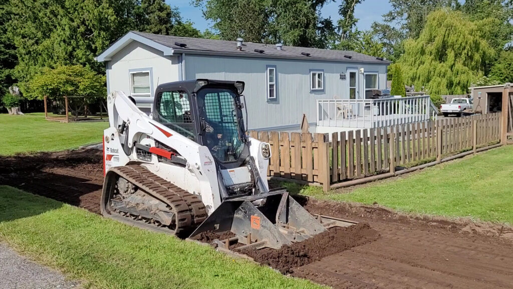 A Bobcat T770 compact track loader performing site preparation next to a house for ROUGH 2 READY in Auburn, AL