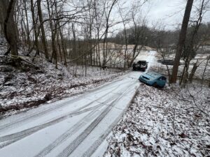 A B&R Towing and Automotive truck recovering a light blue car stuck off a snowy road in Knoxville, TN.