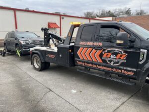 A B&R Towing and Automotive truck towing a dark SUV during the day in Knoxville, TN.