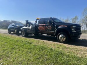 A B&R Towing and Automotive truck towing a dark SUV on a highway in Knoxville, TN.