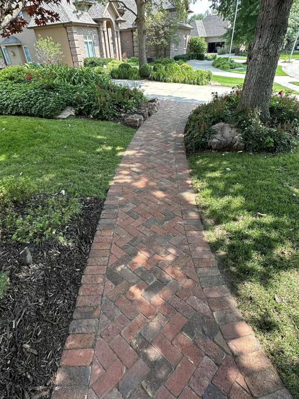A neatly installed brick pathway bordered by freshly mulched garden beds and green lawn by Mitera Landscaping in Papillion, NE.