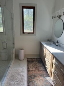 A bright and clean bathroom with a wooden vanity and walk-in shower, tidied by Top-Notch Tidy Services in Chesapeake, VA.