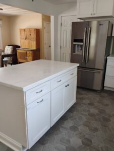 A bright, clean kitchen featuring white cabinets, a large island, and stainless steel refrigerator, cleaned by Tessa's Cleaning Service in Chesapeake, VA.