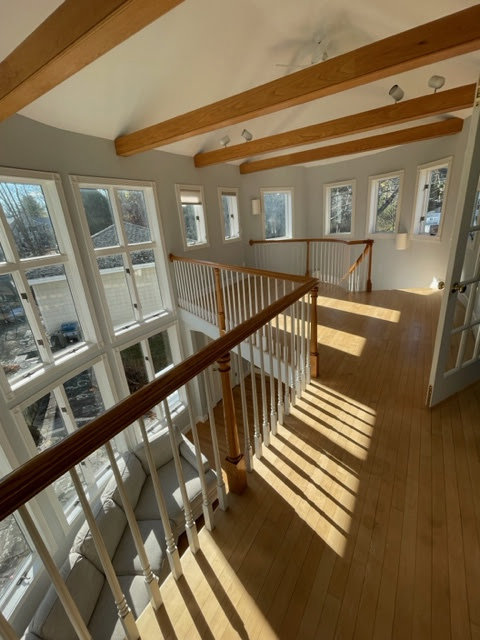 A bright and clean living area with a wooden staircase, maintained by Straight Up Cleaning in South Portland, ME.