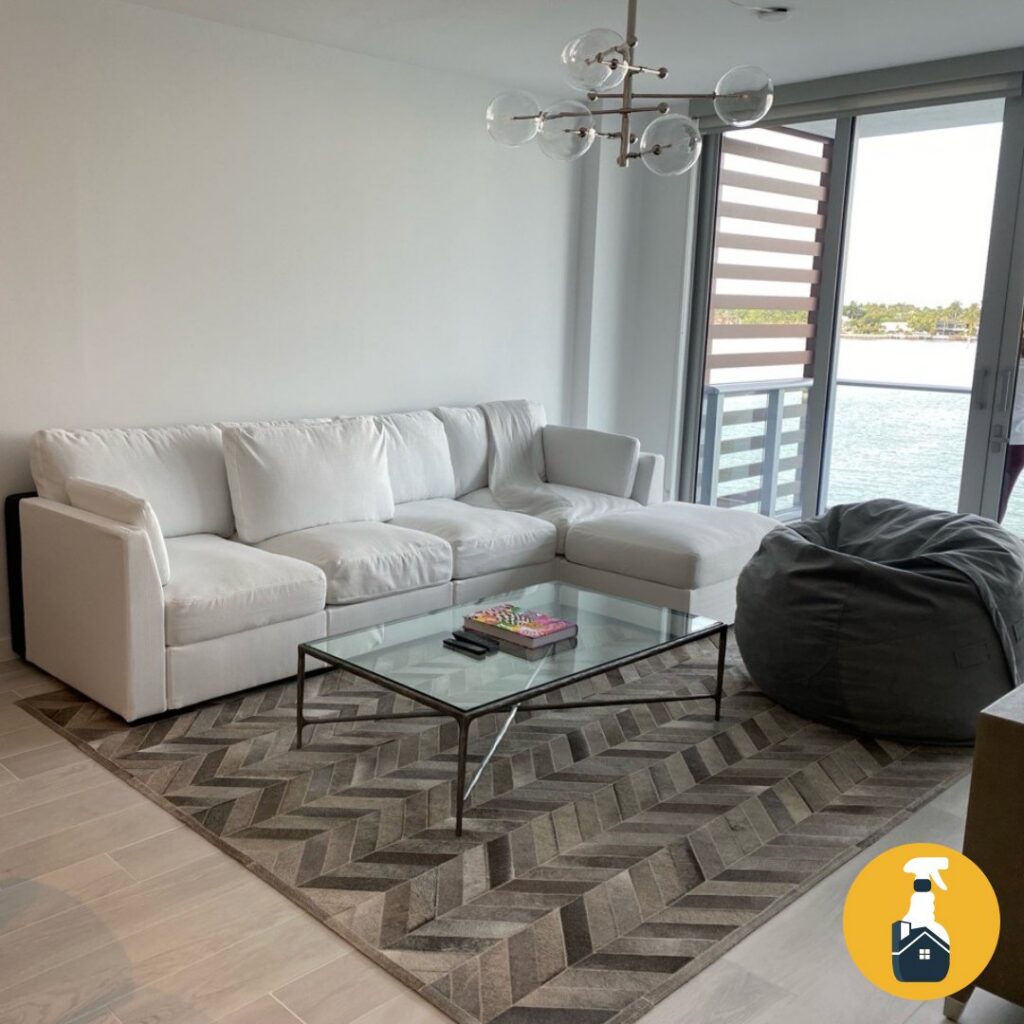 A bright and clean living room with a white sectional sofa and glass coffee table by The Prime Cleaner in Miami, FL.