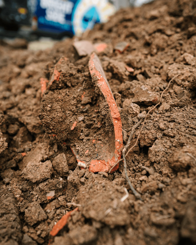 Broken terracotta drain pipe pieces found during excavation by Bright Side Plumbing in Overland Park, KS.