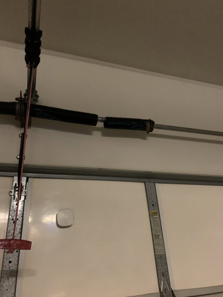 A close-up of a broken garage door torsion spring, indicating a repair job by Cactus Garage Doors, Inc. in North Las Vegas, NV.