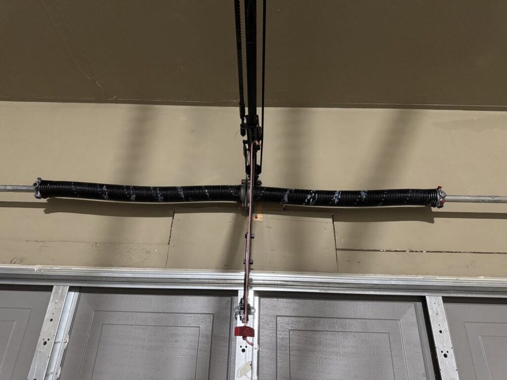 A close-up view of a broken garage door torsion spring, indicating a repair job by Overhead Door Company of Albuquerque in Albuquerque, NM.