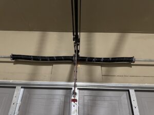 A close-up view of a broken garage door torsion spring, indicating a repair job by Overhead Door Company of Albuquerque in Albuquerque, NM.
