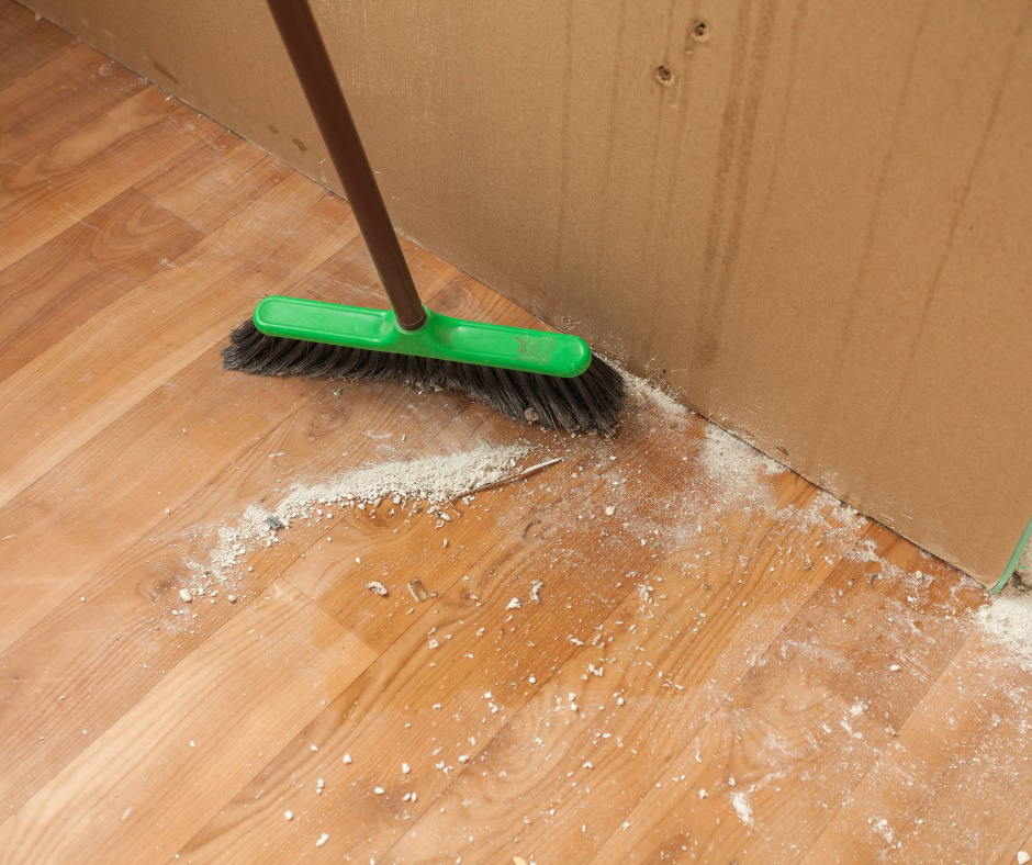 A broom sweeping dust and debris from a wooden floor, representing house cleaning services by Orange Cleaning Services in New Haven, CT
