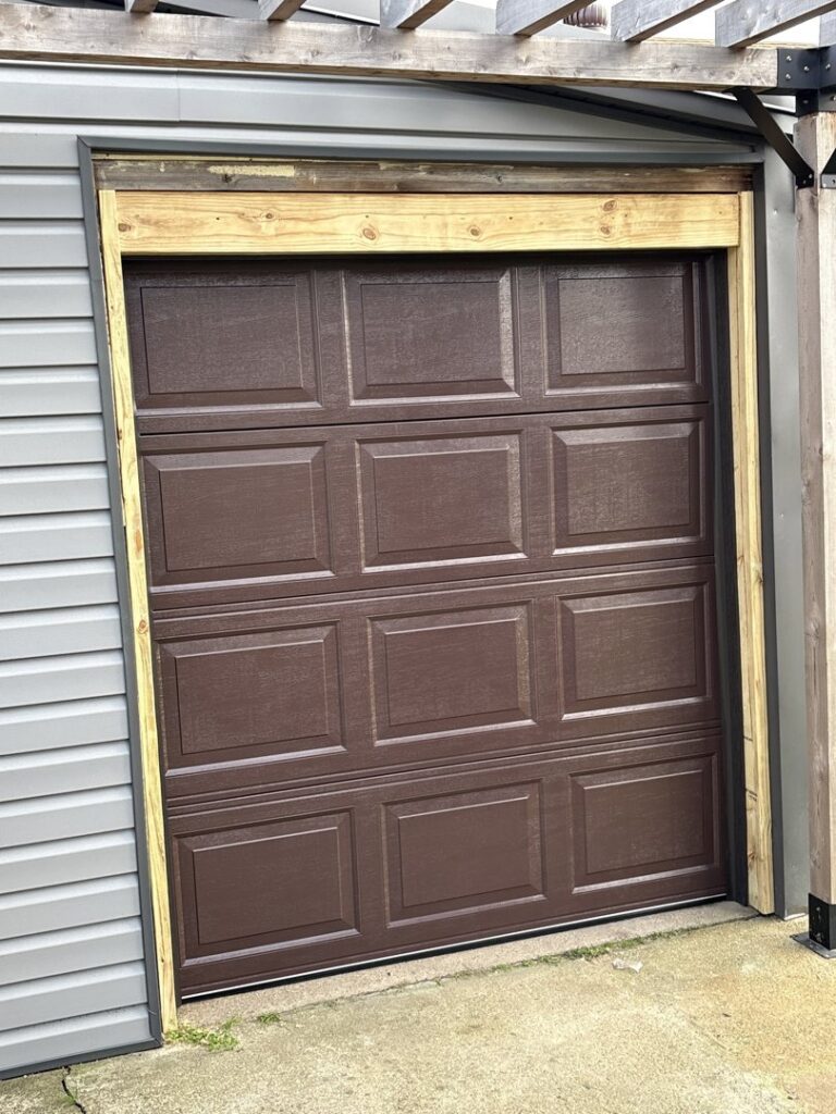 A brown garage door with new wooden framing installed by GRIT Garage Doors in Alma, AR