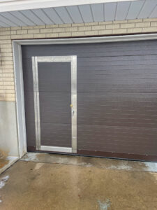 A brown commercial garage door featuring an integrated pass-through door, installed by Canyon Overhead Doors in Salt Lake City, UT.