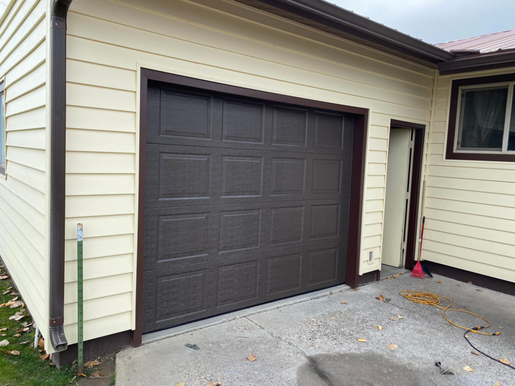 A brown panel garage door recently installed on a residential home by MBP Garage Doors in Firth, ID
