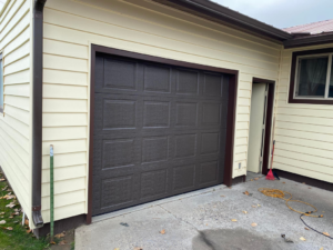 A brown panel garage door recently installed on a residential home by MBP Garage Doors in Firth, ID