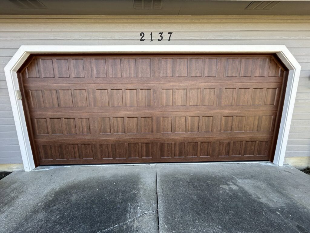 A classic brown panel garage door installed on a residential home by Woodwards Overhead Door Co. in Topeka, KS