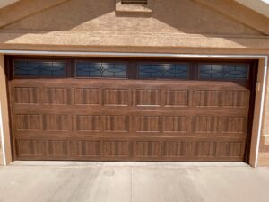 A newly installed brown paneled garage door with decorative top windows by Door Man LLC in Albuquerque, NM.