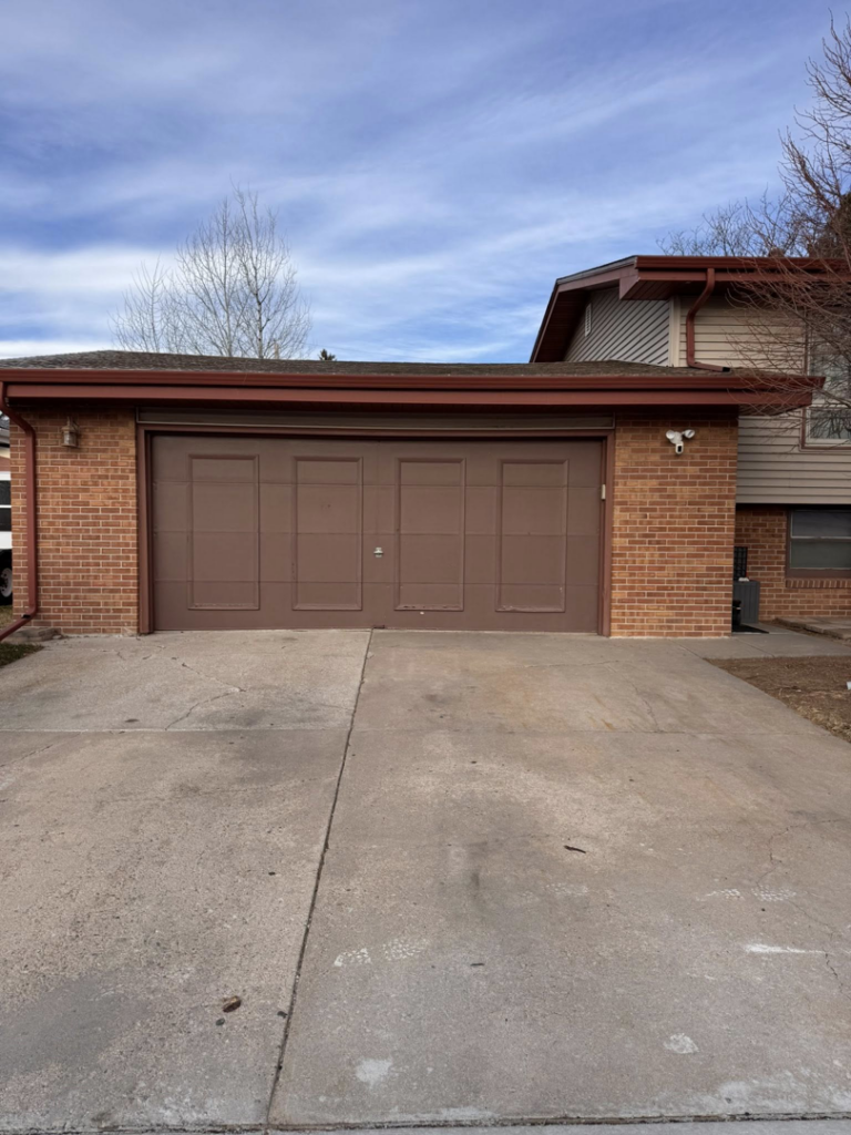 A brown paneled residential garage door installed by Cowboy State Garage Doors, LLC in Cheyenne, WY.