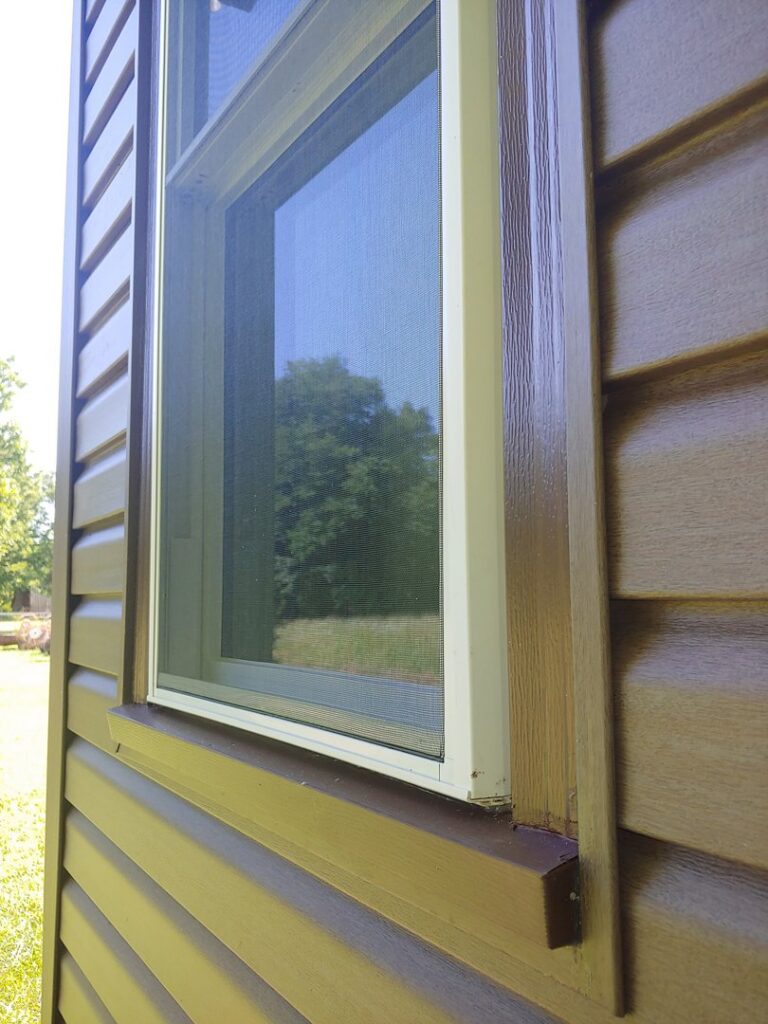 New brown vinyl siding installed around a window on a home by River City Exteriors in San Antonio, TX
