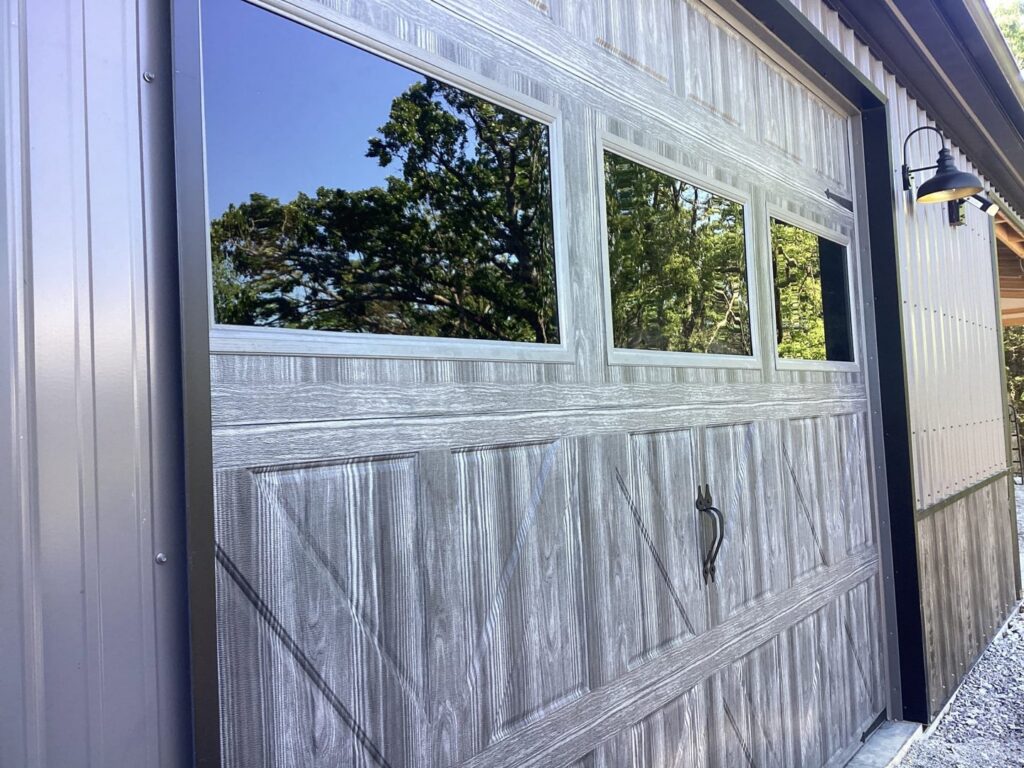 A brown wood-grain garage door with decorative windows installed by Fayetteville Garage Door Co. in Fayetteville, AR