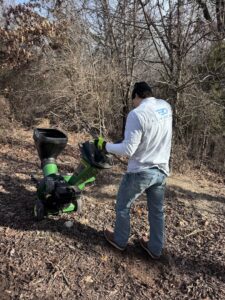 A worker operating a wood chipper for brush clearing by All in- Landscaping and Power-washing in Fayetteville, AR.