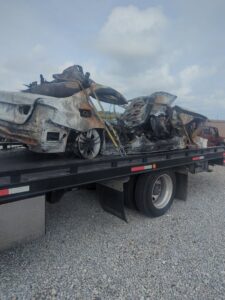 A burned-out car being recovered and transported on a flatbed tow truck by First Hand Towing & Recovery in Fort Wayne, IN.