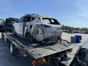 A burnt white SUV secured on a flatbed tow truck by Southeastern Towing and Transport in Savannah, GA.