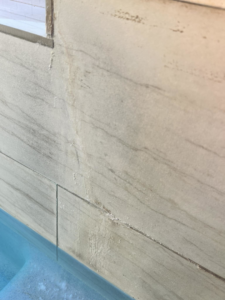 Close-up of calcium buildup and dirt on pool tiles at the waterline, showing a common issue addressed by Aloha Pool Cleaning LLC in Las Vegas, NV.