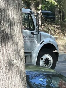A Capital Relocation Group moving truck with branding visible, partially obscured by a tree in Raleigh, NC.