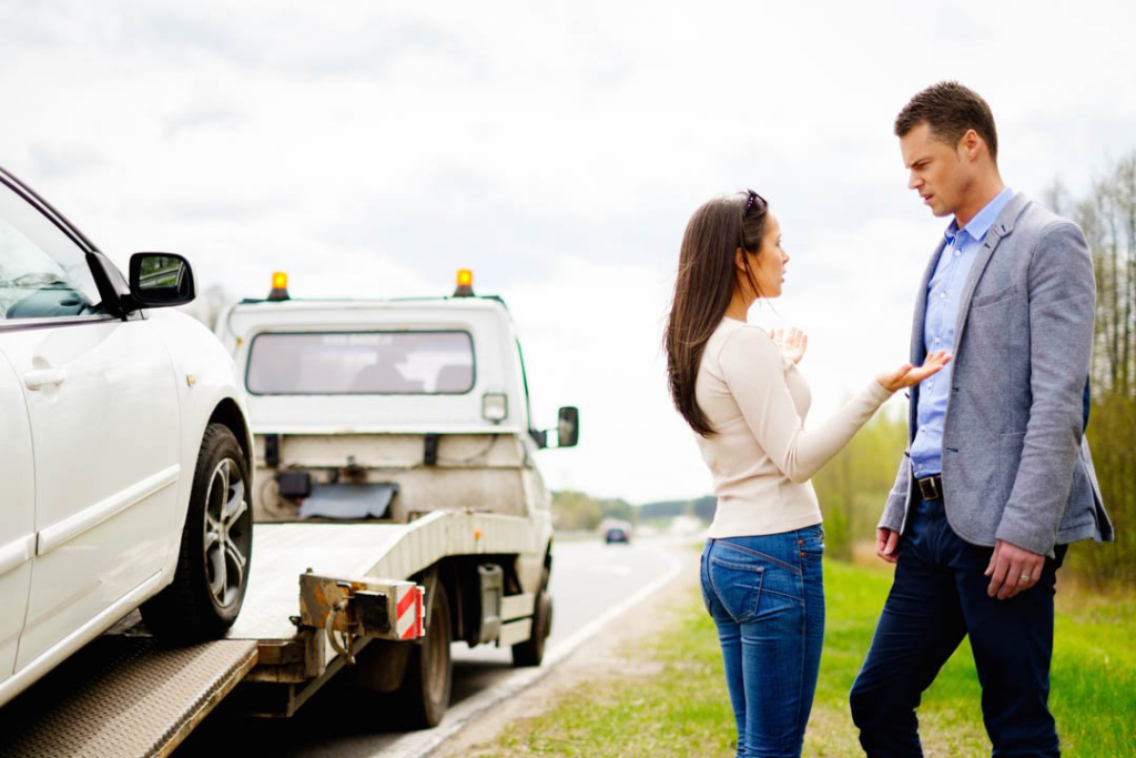 A white car being loaded onto a flatbed tow truck on the roadside by On Time Towing Houston, TX.