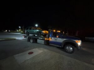 A car being transported on a flatbed tow truck on the highway by Hampton Roads Towing Services in Chesapeake, VA.