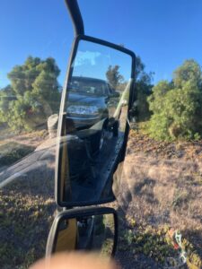 A car being towed on a flatbed truck, visible in the side mirror of a Ledesma's Towing vehicle in San Diego, CA.