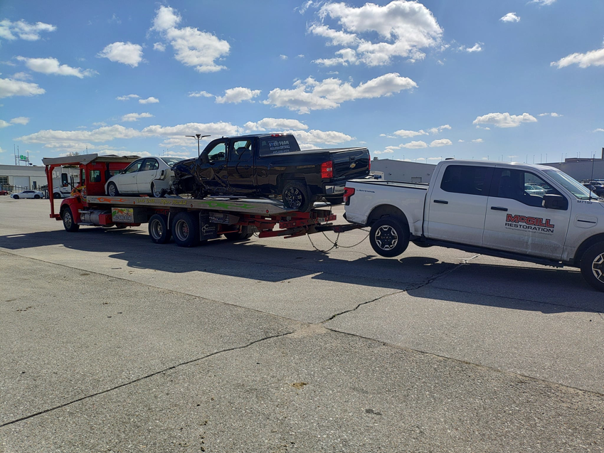 A car carrier truck from Rivera Garcia Towing transporting multiple damaged vehicles and towing a pickup in Omaha, NE.