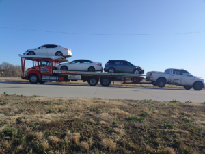 A car carrier truck from Rivera Garcia Towing transporting multiple vehicles, including a damaged pickup, in Omaha, NE.
