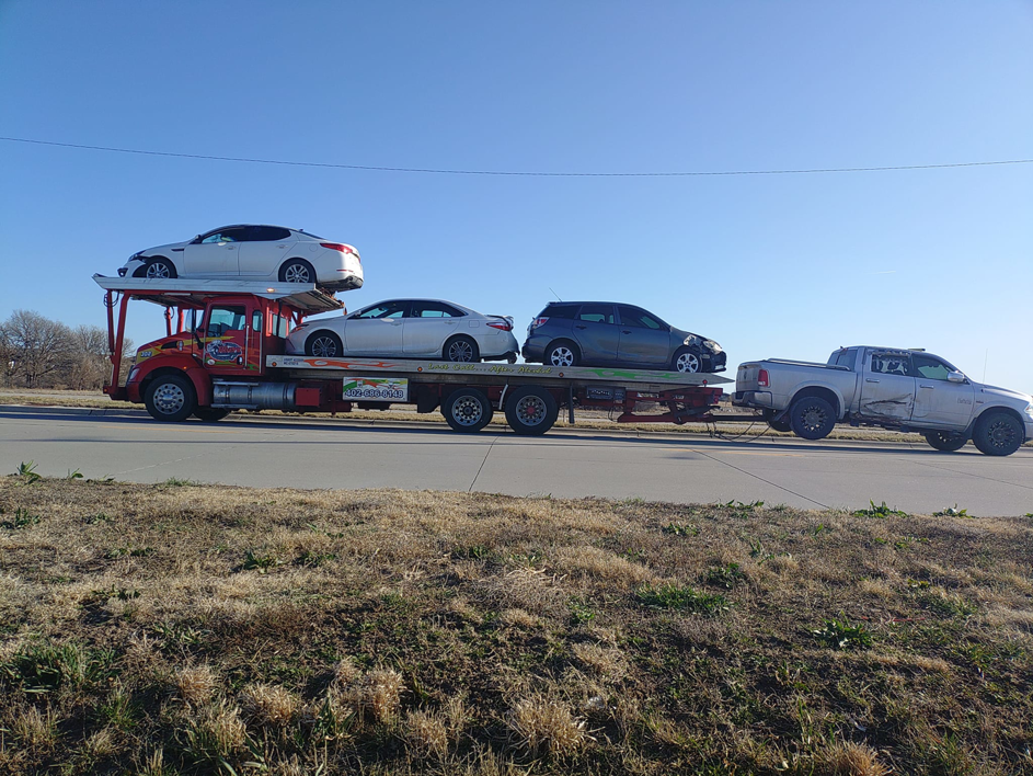 A car carrier truck from Rivera Garcia Towing transporting multiple vehicles, including a damaged pickup, in Omaha, NE.