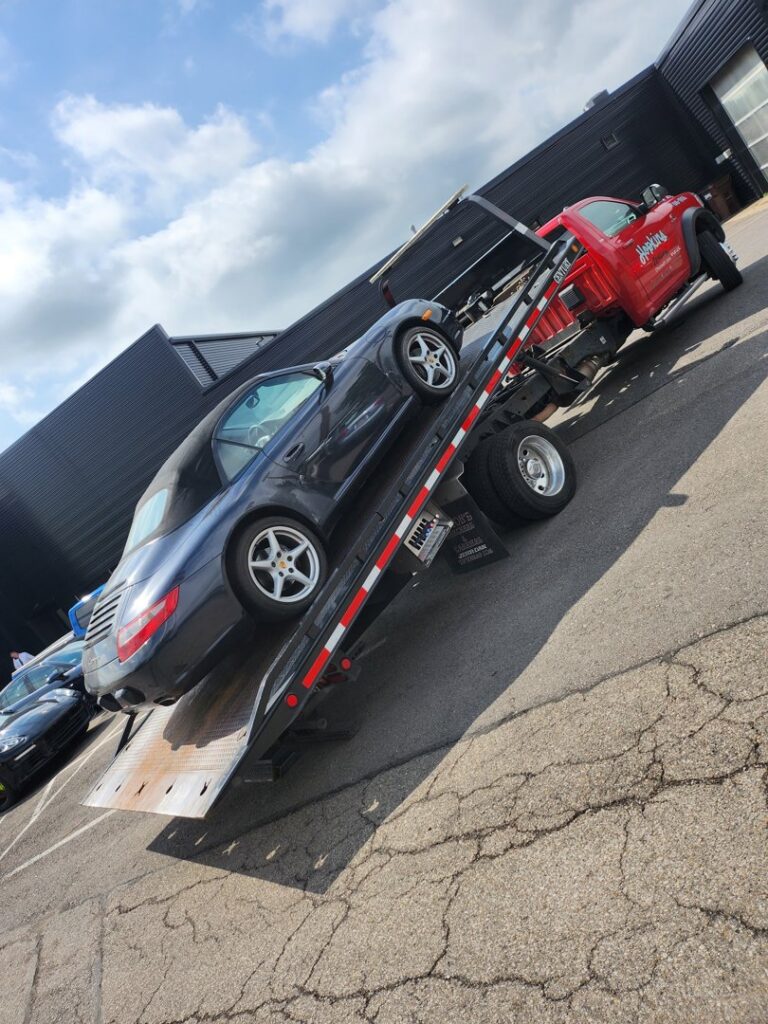 A dark blue convertible car loaded onto a flatbed tow truck by Hopkins Towing in Cincinnati, OH.