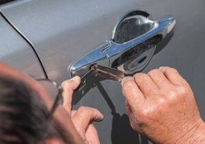 A technician performing a car lockout service, using tools to open a car door, provided by Emergency Towing Sacramento, CA.