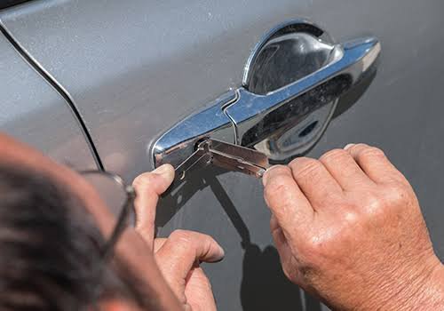 A technician performing a car lockout service, using tools to open a car door, provided by Emergency Towing Sacramento, CA.
