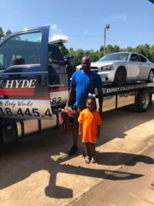 A white car loaded onto a flatbed tow truck by Ray Hyde Paint & Body Works in Alexandria, LA.