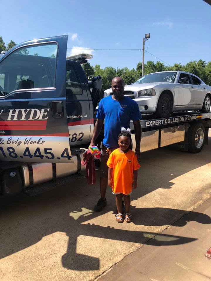 A white car loaded onto a flatbed tow truck by Ray Hyde Paint & Body Works in Alexandria, LA.