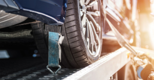 A close-up of a car tire securely strapped onto a flatbed tow truck by Atlantis Towing Services in Chicago, IL.