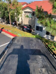 A car stuck in a ditch, viewed from the back of a tow truck, showing recovery services by Cali kings Towing in San Diego, CA.