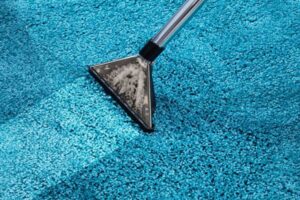 A carpet cleaning wand extracting dirt and water from a blue carpet, a service provided by Orange Cleaning Services in Stamford, CT.