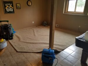 Carpet drying in a room with professional air movers and dehumidifiers, part of water damage restoration by Elite Restoration LLC in Puyallup, WA.