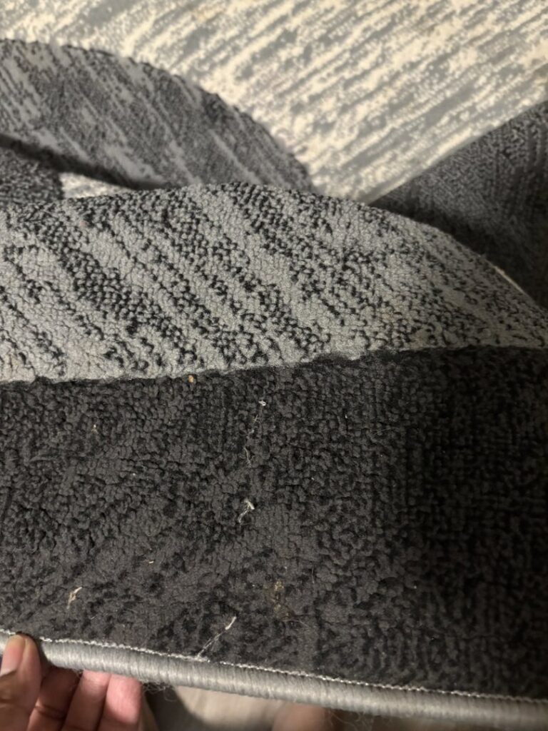 A hand lifting a section of carpet to inspect for mold or water damage underneath, a service provided by COIT Cleaning and Restoration in Indianapolis, IN