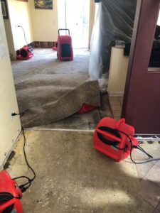 Carpet pulled back to reveal a wet subfloor with drying equipment by EZ Water Damage Restoration Services for water damage in Chula Vista, CA.