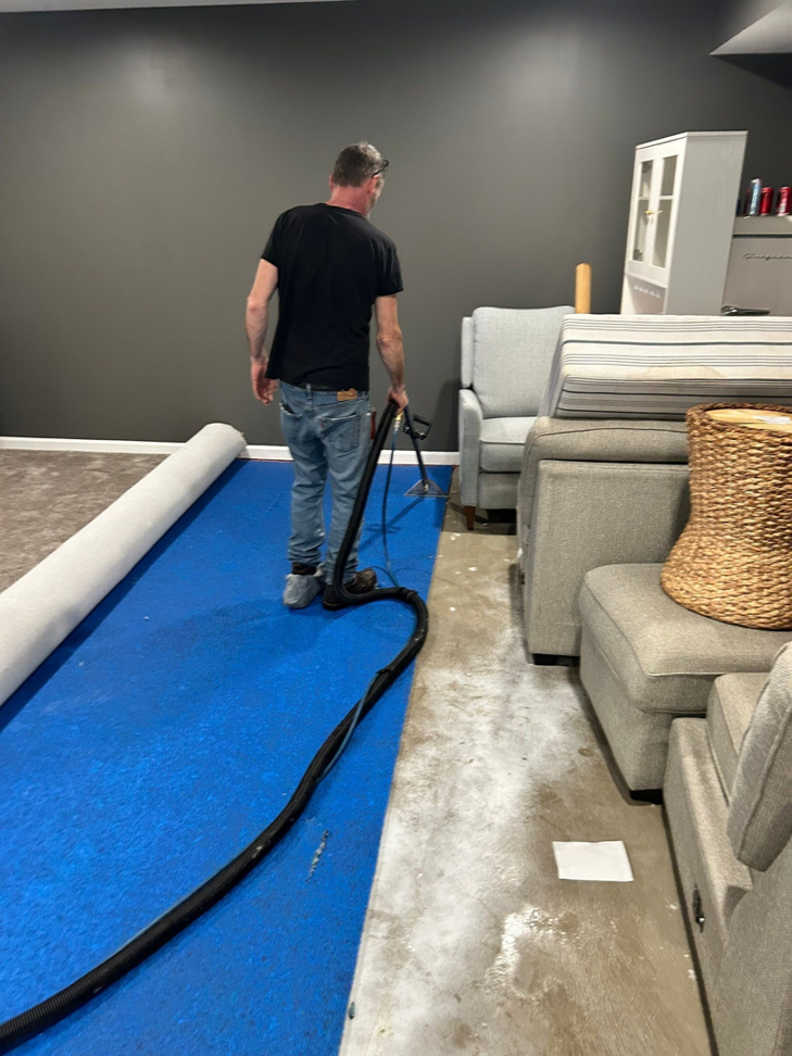 A water damage specialist performing carpet water extraction and drying in a residential basement for H2O Pros Water Restoration Services in Westland, MI.